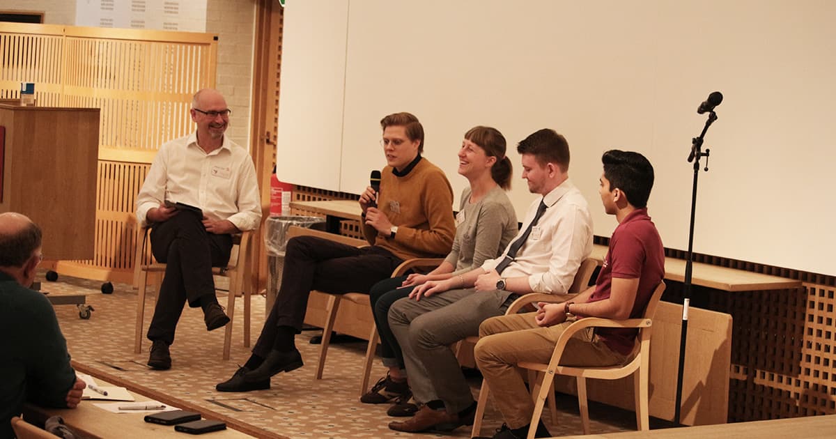 Five people seated in a row on stage for the Young APLers' Panel, including Stephen Taylor, Alve Björk, Yuliia Serhiienko, James Heslip, and Josh David, engaged in a discussion with microphones.