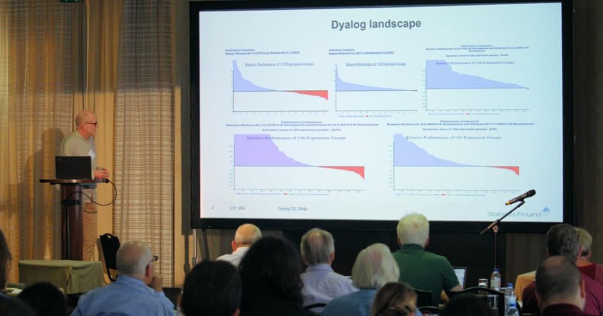 Veli-Matti Jantunen presenting at Dyalog '22 in Olhão, Portugal, analysing Dyalog performance across versions with a slide showing comparative bar graphs of expression group performance.