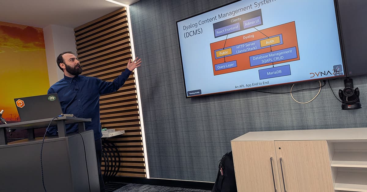 Rich Park presenting at DYNA26, gesturing towards a screen showing a diagram of the Dyalog Content Management System.
