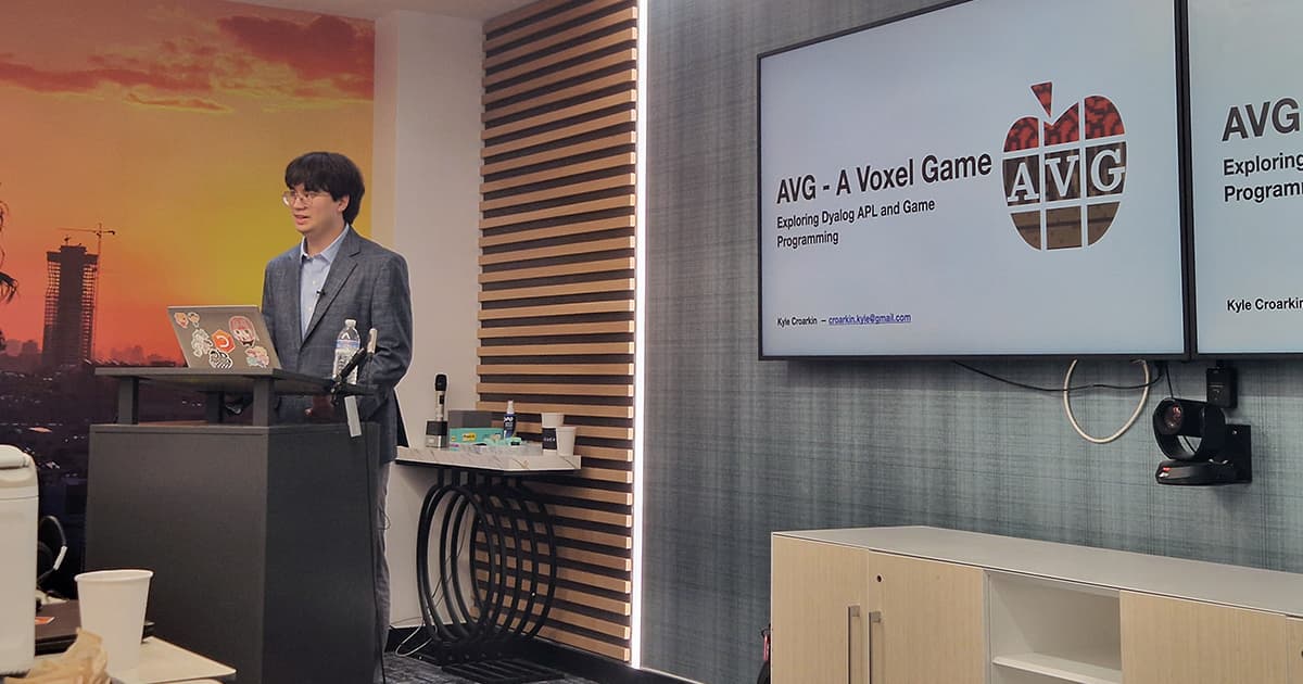 Kyle Croarkin presenting AVG - A Voxel Game at DYNA26, standing at a lectern beside screens showing the title slide.