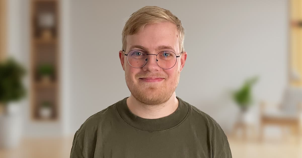 Peter Mikkelsen smiling indoors with a softly blurred background of a modern room.
